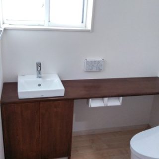 造り付けの手洗いカウンターのチョコレートブラウンがシック。窓から差し込む光で明るいトイレ空間に