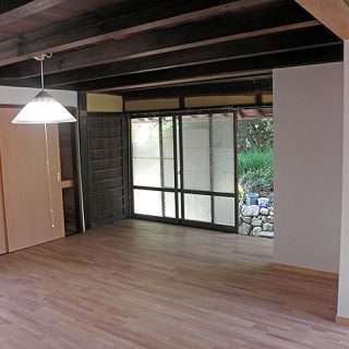 障子建具を取り払い、開放的な部屋に生まれ変わりました。重厚な梁と清潔感ある白い壁、無垢のフローリングがシックで調和のとれた空間に。